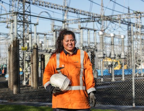 Female electricity worker in front of power plant