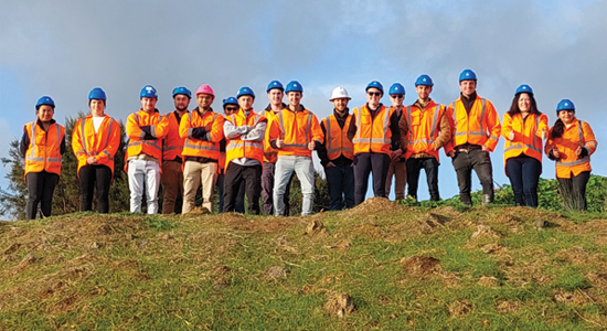 Group of works in hi vis on top of a hill smiling